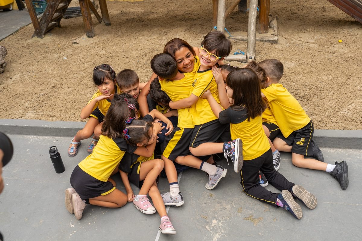 Professora abraçada por um grupo de crianças