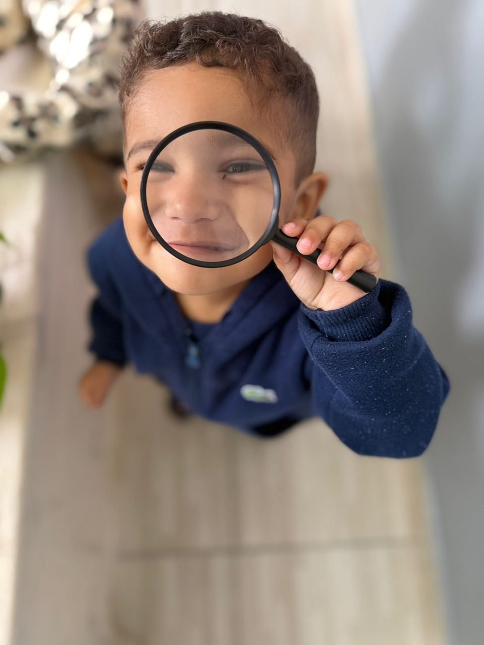 Criança explorando com lupa no ateliê da Escola Abelha Rainha