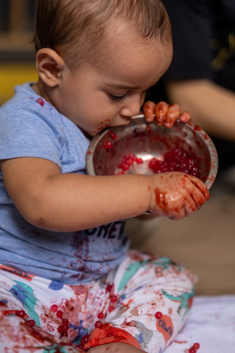 Bebê explorando frutas e potinho de metal