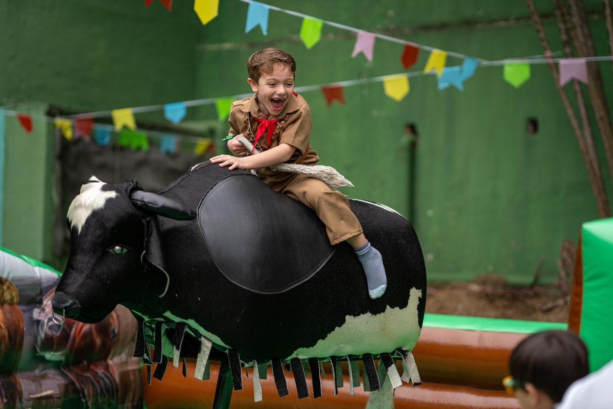 Criança sorrindo no touro mecânico durante festa junina